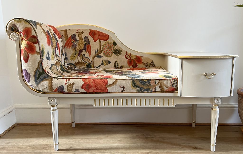 A telephone seat re-upholstered with a cream and multi-colour fabric with birds and florals.
