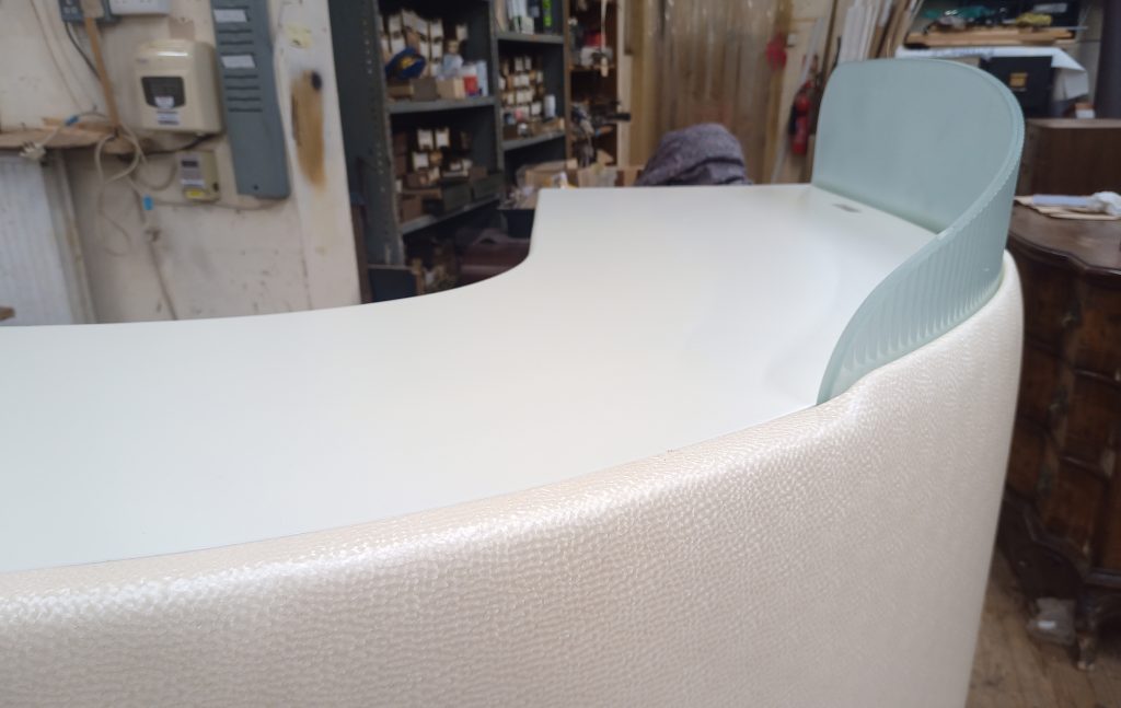 A white custom reception desk with faux ostrich leather and frosted glass.