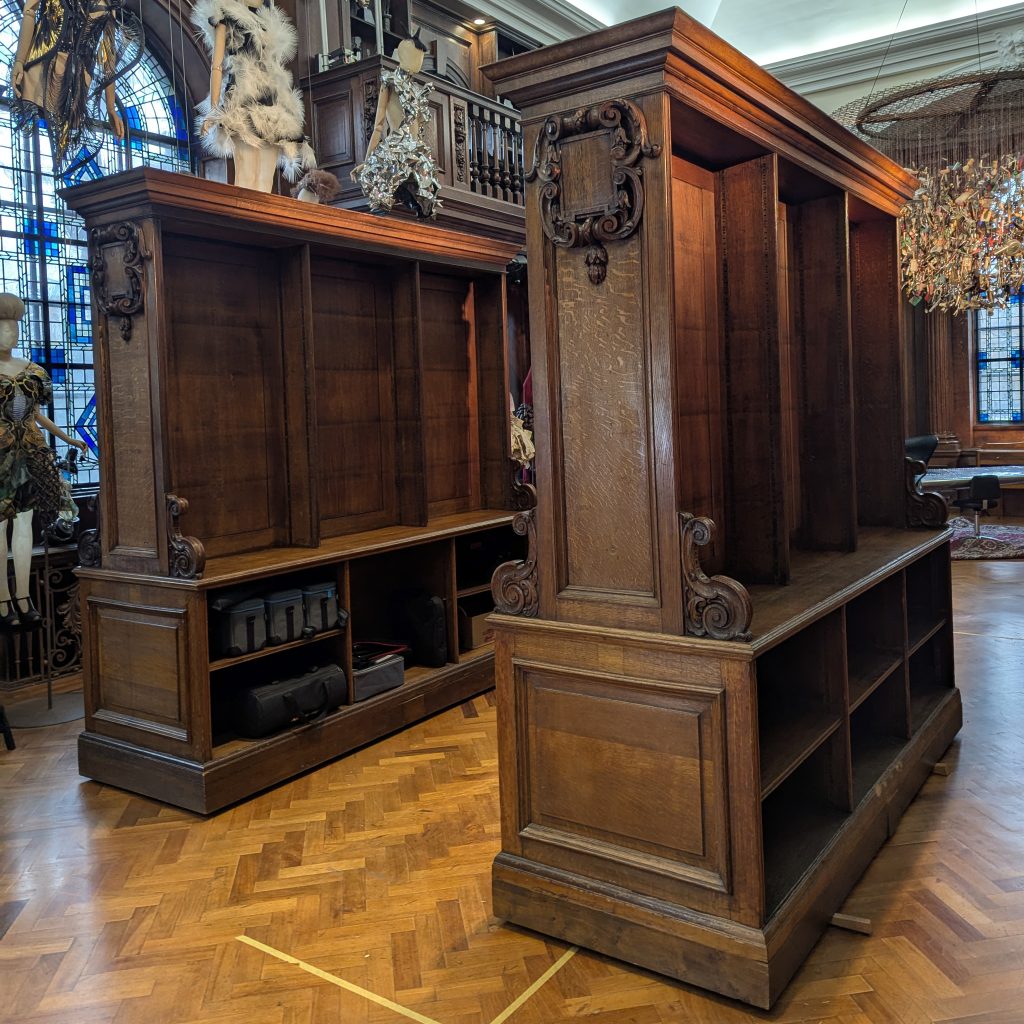 Polished antique wooden bookcases in an ornate room with stained glass windows and parquet flooring.