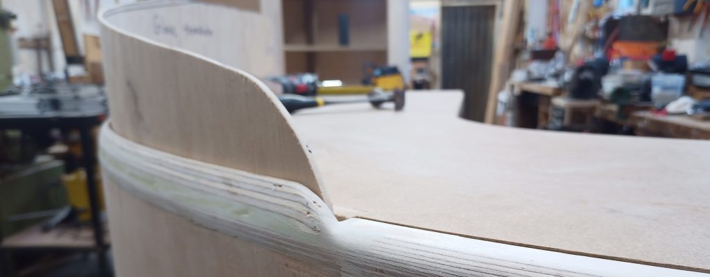 Closeup of a bespoke wooden reception desk in progress in a woodworking workshop.